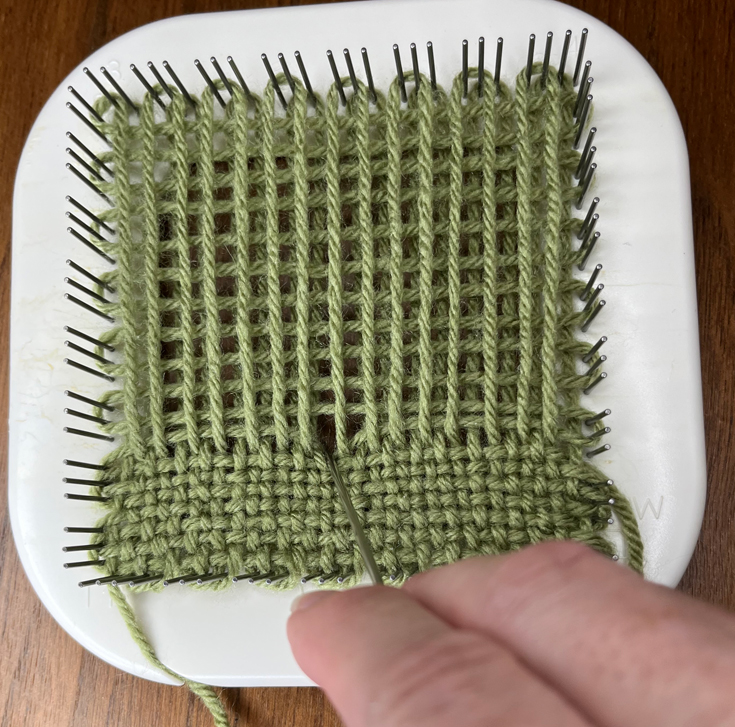 packing yarn strands on pin loom with weaving needle